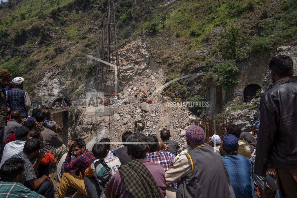 Dar Yasin Villagers watch from distance as earth movers dig through rubble of a collapsed tunnel in Ramban district, south of Srinagar, Indian controlled Kashmir, Friday, May 20, 2022. An official in Indian-controlled Kashmir said Friday that 10 workers were trapped after part of a road tunnel collapsed in the Himalayan region. (AP Photo/Dar Yasin)