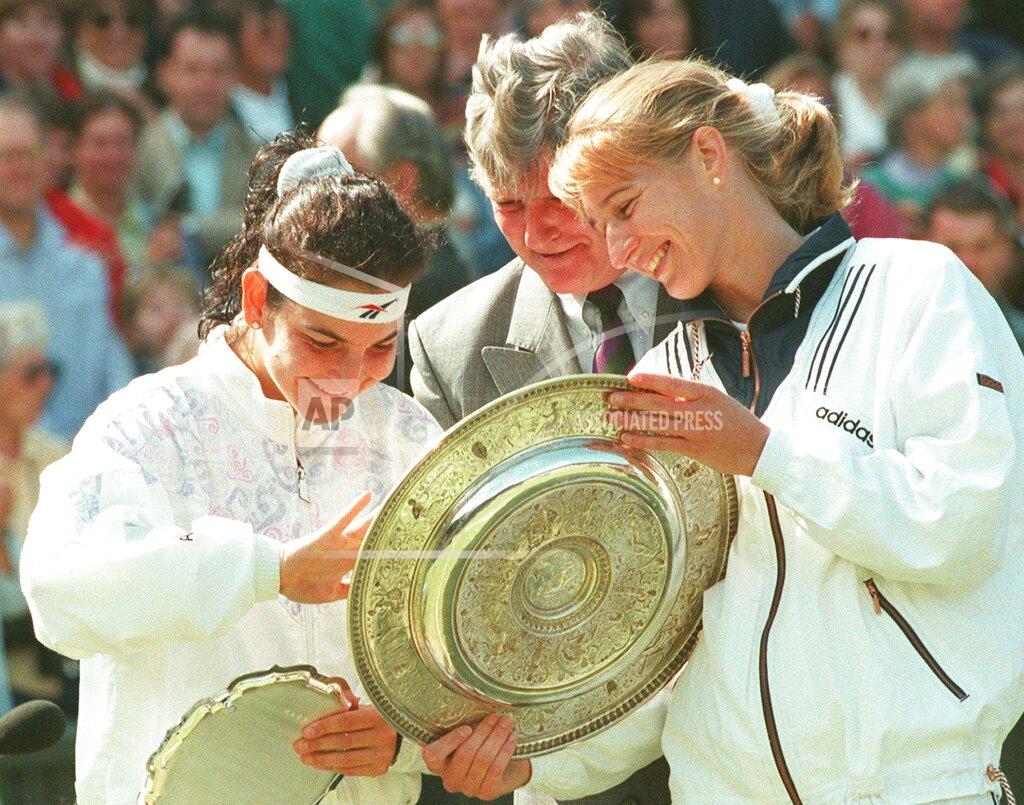 Dave Caulkin FILE - In this July 6, 1996, file photo, 1996 women's singles champion Steffi Graf, right, examines the the winners trophy with the runner up, Arantxa Sanchez-Vicario, left and Tournament referee Alan Mills after the presentation ceremony on Wimbledon's Centre Court. Graf won the match in straight sets 6-3, 7-5 to capture her seventh singles title. (AP Photo/Dave Caulkin, File)