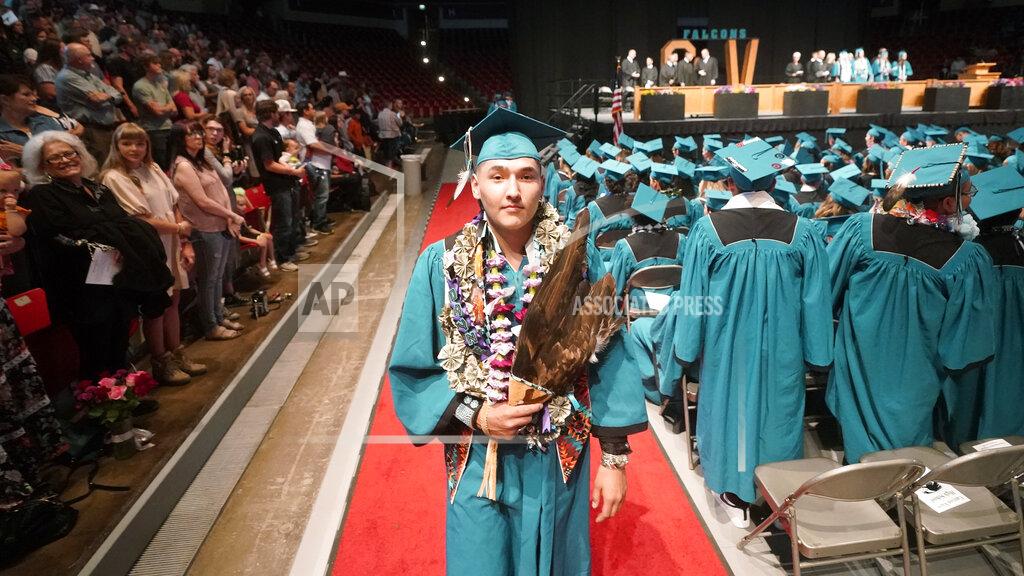 Rick Bowmer Dayne Hudson, member of the Paiute Indian Tribe of Utah, walks with his eagle feather fan during the Canyon View High School graduation Wednesday, May 25, 2022, in Cedar City, Utah. Hudson said it was important to wear eagle feathers and a beaded cap to represent his family and honor those who were stopped from doing so under the old rule. (AP Photo/Rick Bowmer)