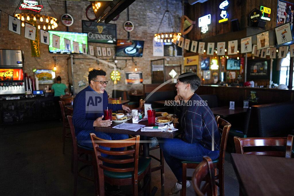 David J. Phillip Tasha Arevalo, right, laughs with Joseph Butler while eating at Mo's Irish Pub, Tuesday, March 2, 2021, in Houston. Texas Gov. Greg Abbott announced that he is lifting business capacity limits and the state's mask mandate starting next week. (AP Photo/David J. Phillip)