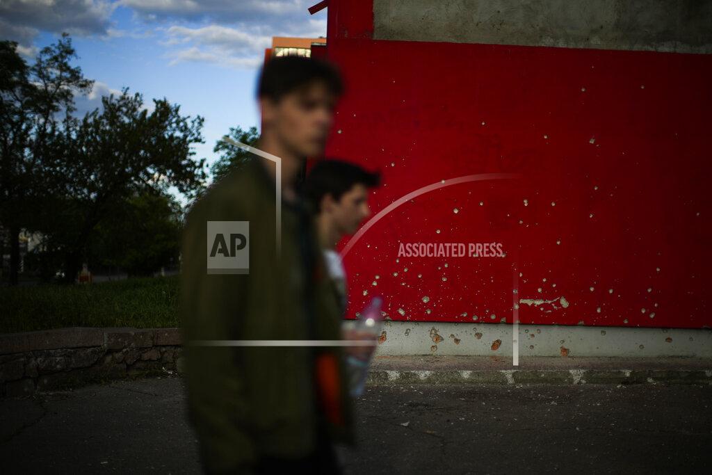 Francisco Seco Youngsters walk past a wall scarred by shrapnel after a bombing earlier in the day in Mykolaiv, Ukraine, Monday, May 16, 2022. (AP Photo/Francisco Seco)
