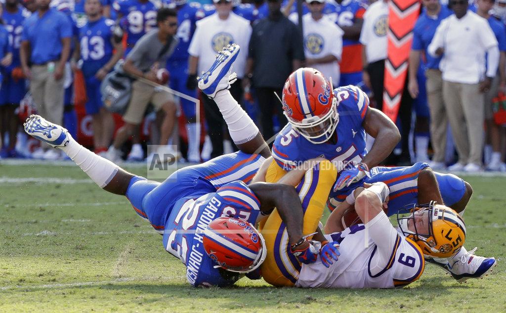 John Raoux LSU quarterback Joe Burrow (9) is tackled by Florida defensive back Chauncey Gardner-Johnson (23) and defensive back CJ Henderson, right, after running for a first down during the first half of an NCAA college football game, Saturday, Oct. 6, 2018, in Gainesville, Fla. (AP Photo/John Raoux)