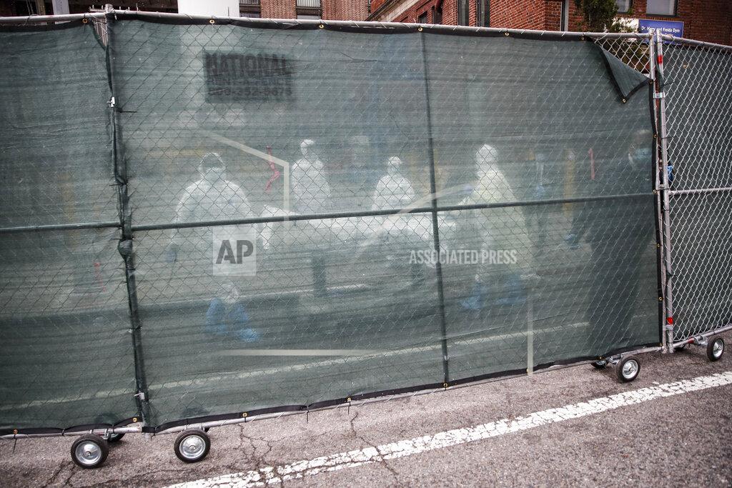 John Minchillo FILE - In this April 9, 2020, file photo, medical workers wearing personal protective equipment due to COVID-19 concerns move a body behind a fence at The Brooklyn Hospital Center, in the Brooklyn borough of New York. The U.S. death toll from COVID-19 has topped 500,000 — a number so staggering that a top health researchers says it is hard to imagine an American who hasn't lost a relative or doesn't know someone who died. (AP Photo/John Minchillo, File)