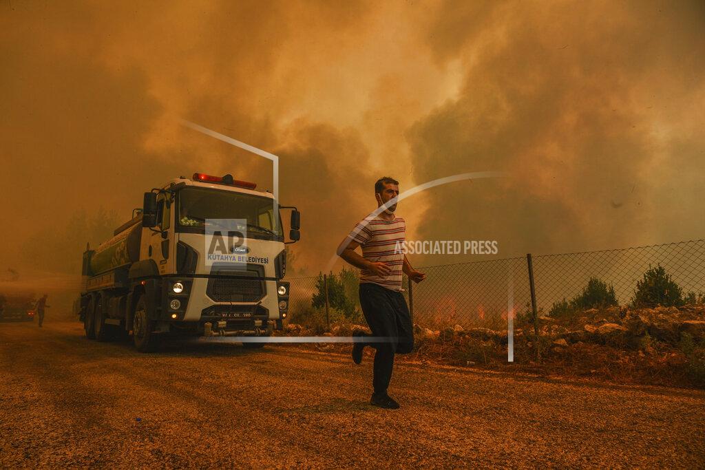 Uncredited A man runs, in the fire-devastating Sirtkoy village, near Manavgat, Antalya, Turkey, Sunday, Aug. 1, 2021. More than 100 wildfires have been brought under control in Turkey, according to officials. The forestry minister tweeted that five fires are continuing in the tourist destinations of Antalya and Mugla. (AP Photo)