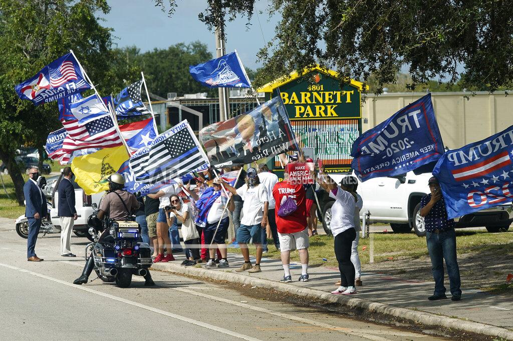 John Raoux A group of President Donald Trump supporters wave flags along the street as Democratic vice presidential candidate Sen. Kamala Harris, D-Calif., arrives at a campaign eventMonday, Oct. 19, 2020, in Orlando, Fla. (AP Photo/John Raoux)