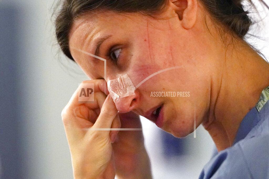 Elaine Thompson FILE - In this Jan. 26, 2021, file photo, with indentations from a N-95 mask marking her face, registered nurse Lilyrose Fox peels protective tape from her nose after working in patients rooms in the COVID acute care unit at UW Medical Center-Montlake, in Seattle. The U.S. death toll from COVID-19 has almost topped 500,000 — a number so staggering that a top health researchers says it is hard to imagine an American who hasn't lost a relative or doesn't know someone who died. (AP Photo/Elaine Thompson, File)