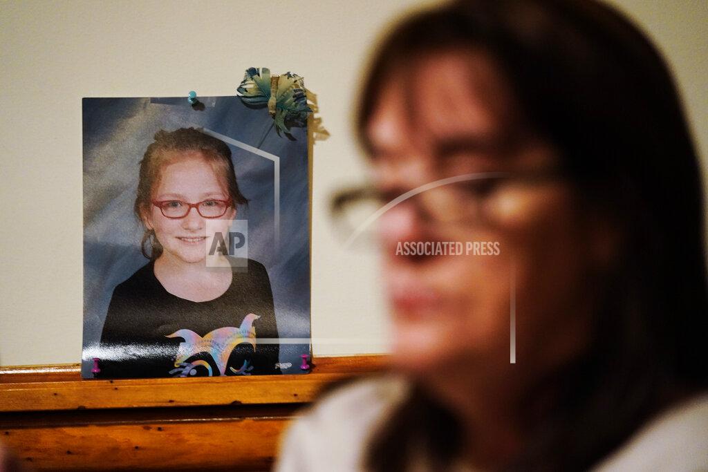 Matt Rourke Patti Burt poses for a portrait near a photo of her granddaughter, 9-year-old Ava Lerario, in Cherry Hill, N.J., Wednesday, March 10, 2021. Burt's daughter Ashley Belson, Ava and Ava's father, Marc Lerario were found shot to death on May 26, 2020. (AP Photo/Matt Rourke)
