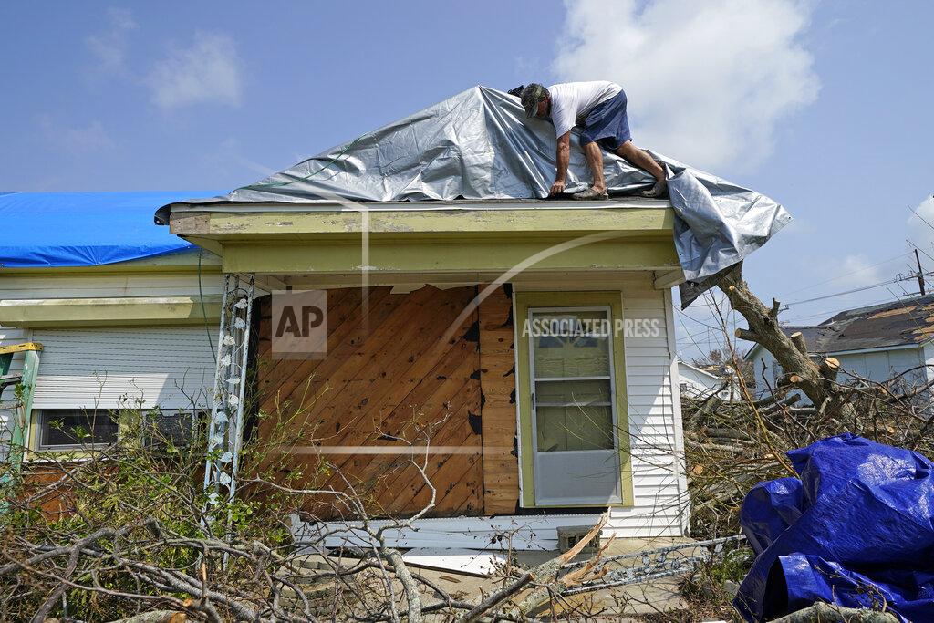 David J. Phillip Gary Johnston works to put a tarp on the roof his mother-in-laws damaged home in the aftermath of Hurricane Ida, Thursday, Sept. 2, 2021, in Golden Meadow, La. (AP Photo/David J. Phillip)