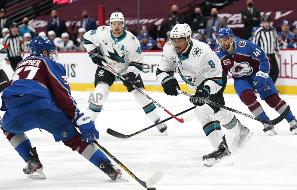 David Zalubowski Colorado Avalanche left wing J.T. Compher, left, tries to collect the puck as San Jose Sharks left wing Evander Kane pursues during the first period of an NHL hockey game Friday, April 30, 2021, in Denver. (AP Photo/David Zalubowski)