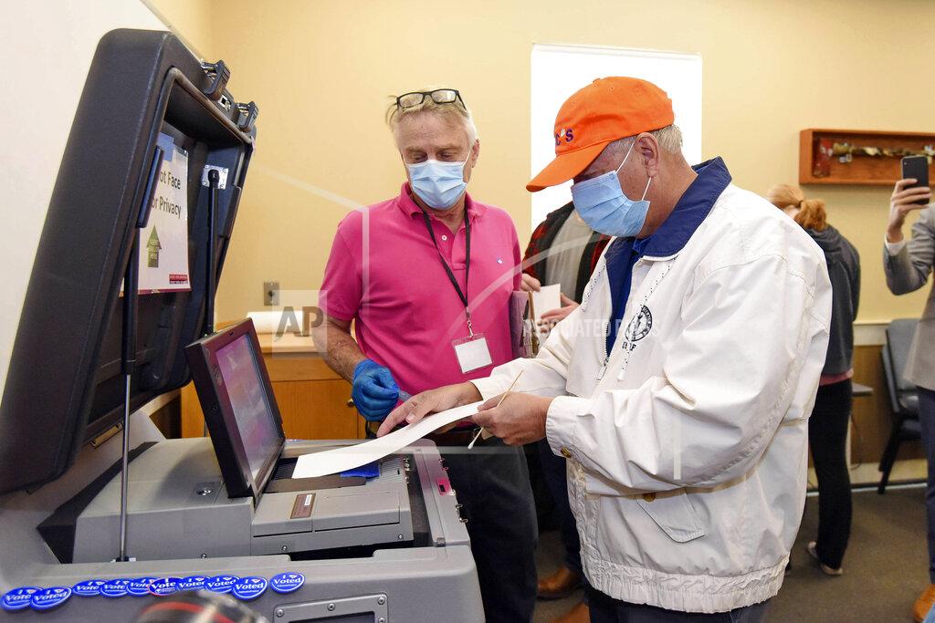 Richard Shiro Republican U.S. Sen. Lindsey Graham, center, delivers his ballot while voting in the general election, Tuesday, Nov. 3, 2020, at the Corinth-Shiloh Fire Dept. in Seneca, S.C. (AP Photo/Richard Shiro)