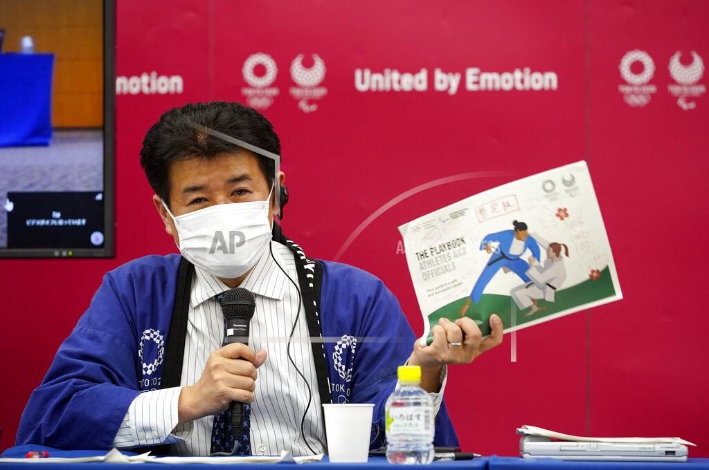 Tokyo 2020 Games Delivery Officer Hidemasa Nakamura holds a sample of the Version Two of Tokyo 2020 Playbook during a press briefing in Tokyo, Japan, 28 April 2021. The IOC and Tokyo 2020 organizers presented the second version of the playbook saying a third version will be unveiled in the coming weeks. (Franck Robichon / Pool via AP)