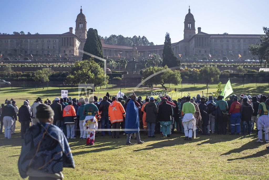 Uncredited Striking miners protest for higher wages at the Union Buildings, background, in Pretoria, South Africa, Tuesday, May 24, 2022 as German Chancellor Olaf Scholz meets with South African President Cyril Ramaphosa on a one-day visit to the country. (AP Photo)