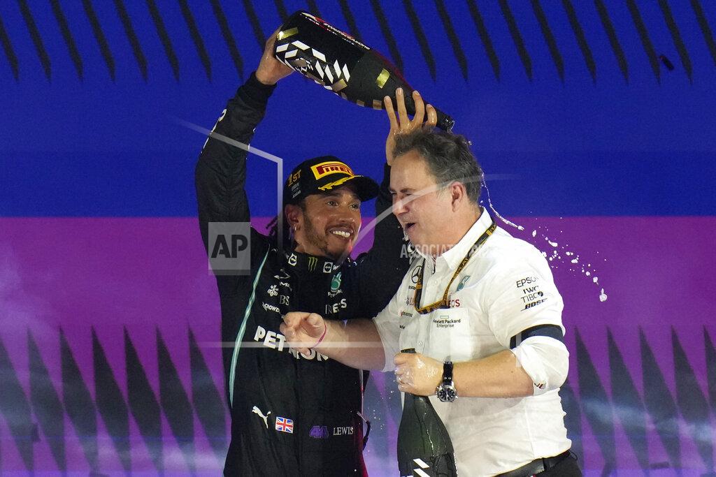 Hassan Ammar Mercedes driver Lewis Hamilton of Britain celebrate with a team member after winning the Formula One Saudi Arabian Grand Prix in Jiddah, Sunday, Dec. 5, 2021. (AP Photo/Hassan Ammar)