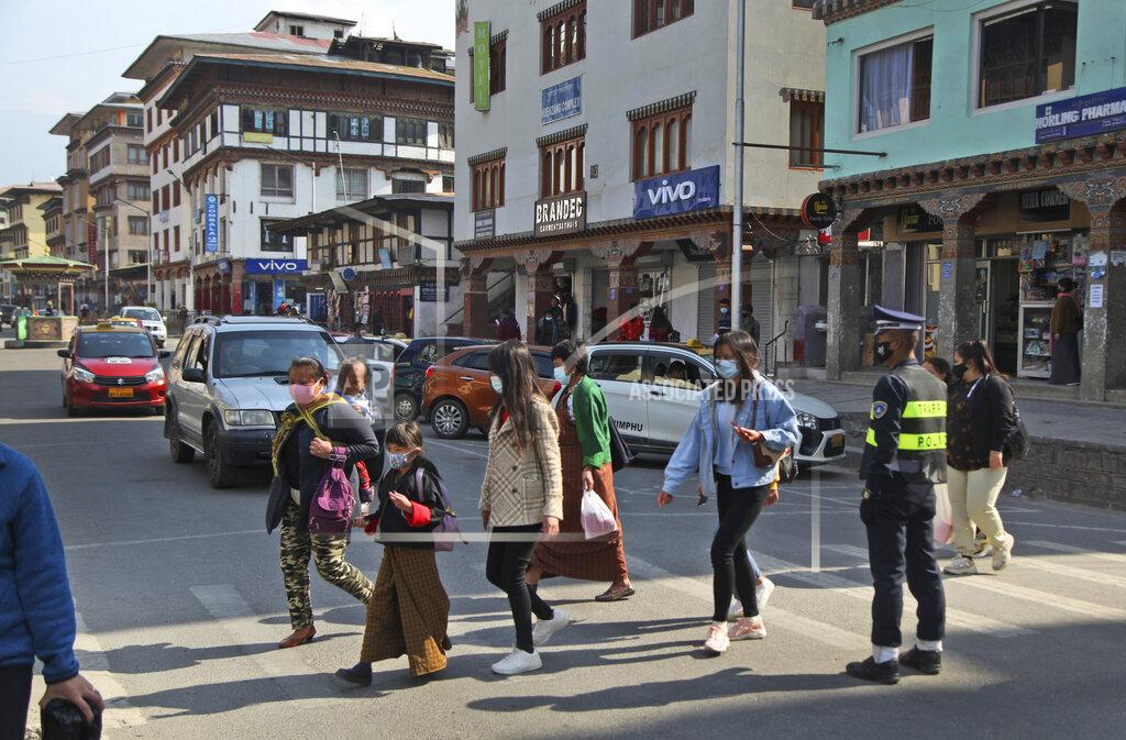 Uncredited Bhutanese people wearing face masks as precaution against coronavirus cross a street in Thimpu, Bhutan, Monday, April 12, 2021. The tiny Himalayan kingdom wedged between India and China has vaccinated nearly 93% of its adult population since March 27. Overall, the country has vaccinated 62% of its 800,000 people. (AP Photo)