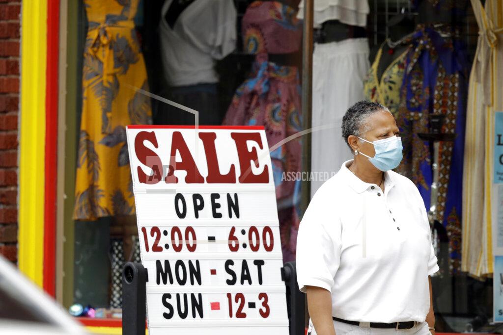 Tony Dejak A woman walks past a boutique with a sale sign, Thursday, June 4, 2020, in Cleveland Heights, Ohio. The state says more than 34,000 Ohioans filed unemployment claims during the last week of May. That is the lowest figure since Ohio's stay-at-home orders depressed the economy and led to widespread layoffs. (AP Photo/Tony Dejak)