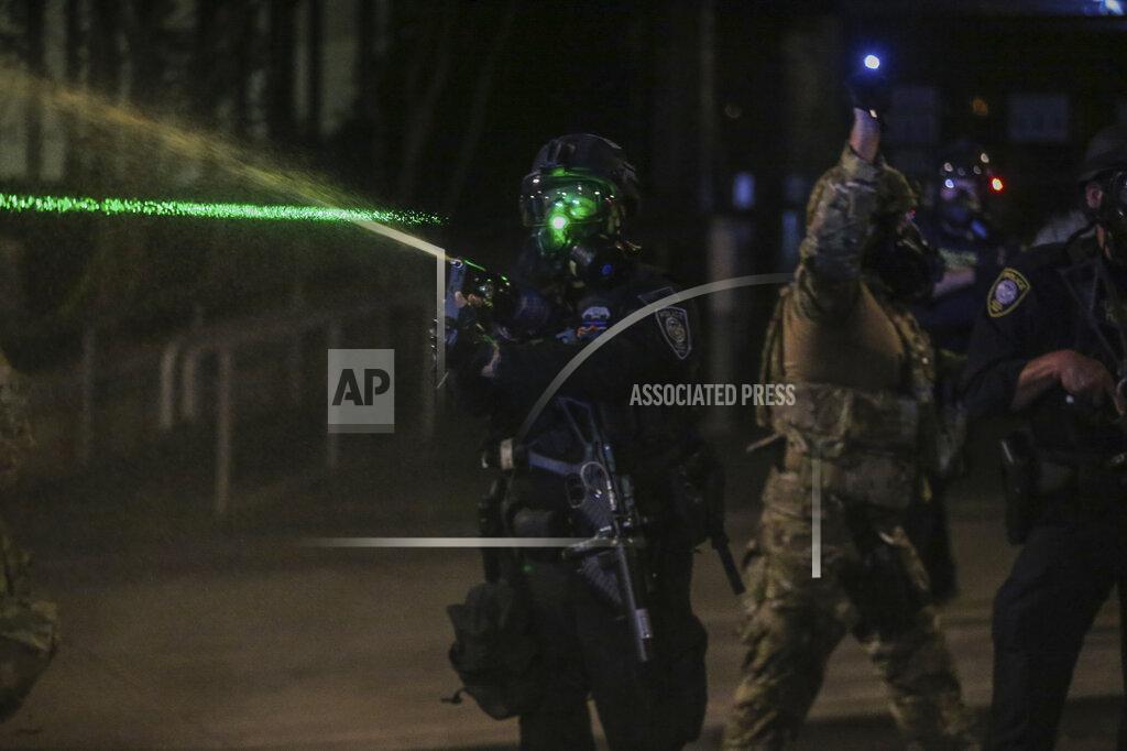 Dave Killen Police respond to protesters during a demonstration, Friday, July 17, 2020 in Portland, Ore. Militarized federal agents deployed by the president to Portland, fired tear gas against protesters again overnight as the city’s mayor demanded that the agents be removed and as the state’s attorney general vowed to seek a restraining order against them. (Dave Killen/The Oregonian via AP)