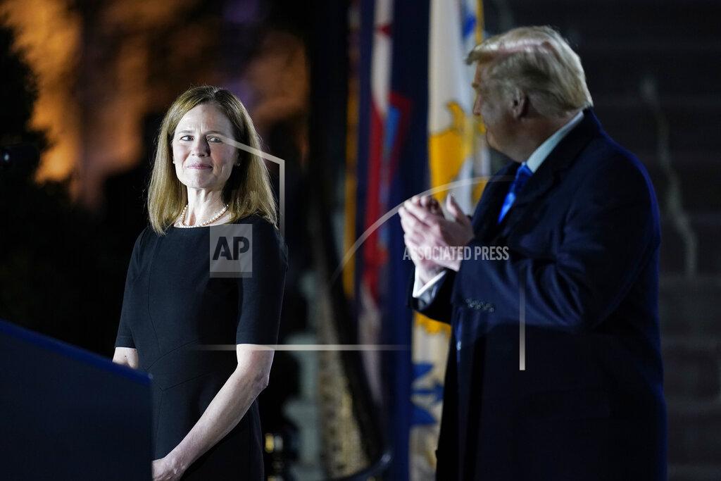 President Donald Trump looks toward Amy Coney Barrett, before Supreme Court Justice Clarence Thomas administers the Constitutional Oath to her on the South Lawn of the White House in Washington, Monday, Oct. 26, 2020, after Barrett was confirmed by the Senate earlier in the evening. (AP Photo/Patrick Semansky)