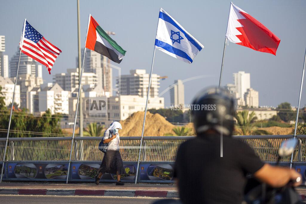 Ariel Schalit A woman wearing a face mask against the coronavirus pandemic walks past American, United Arab Emirates, Israel and Bahraini flags at the Peace Bridge in Netanya, Israel, Monday, Sept. 14, 2020. For the first time in more than a quarter-century, a U.S. president will host a signing ceremony between Israelis and Arabs at the White House, billing it as an "historic breakthrough" in a region long known for its stubborn conflicts. (AP Photo/Ariel Schalit)