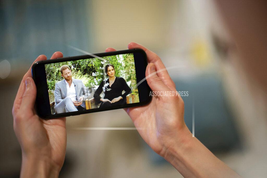 Aaron Chown A man watches a phone screen showing an interview of Prince Harry and Meghan, The Duchess of Sussex, by Oprah Winfrey, in London Monday, March 8, 2021. (Aaron Chown/PA via AP)