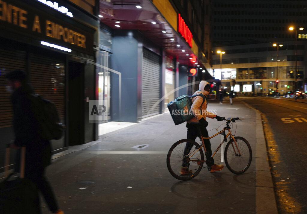 FILE - In this file photo dated Monday Feb. 15, 2021, a Deliveroo food delivery worker pushes his bike in front of restaurant in Paris. Shares in the app-based meal delivery service Deliveroo tumbled by as much as a third in their U.K. stock market debut on Wednesday March 31, 2021. (AP Photo/Francois Mori, FILE)