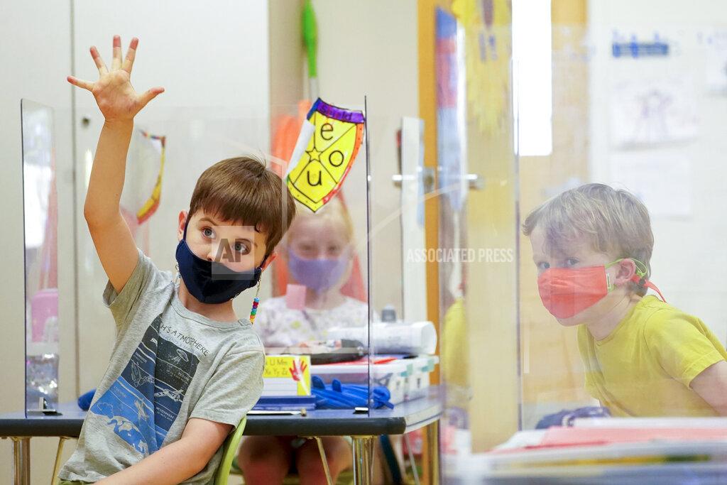 Mary Altaffer FILE - Kindergarten students wear their masks and are separated by plexiglass during a math lesson at the Milton Elementary School, Tuesday, May 18, 2021, in Rye, N.Y. Gov. Andrew Cuomo said Monday that students no longer have to wear masks while outdoors on school grounds. But students and staff will still have to wear masks for the rest of the school year.(AP Photo/Mary Altaffer, File)