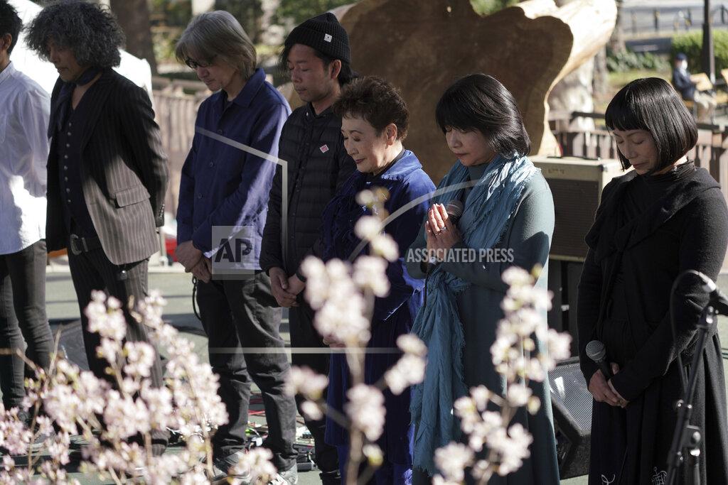 Eugene Hoshiko Artists and staff members at the stage stand to mourn for the victims of the 2011 earthquake and tsunami during an online special memorial event at Hibiya Park in Tokyo Thursday, March 11, 2021. Japan on Thursday marked the 10th anniversary of the massive earthquake, tsunami and nuclear disaster that struck Japan's northeastern coast. (AP Photo/Eugene Hoshiko)