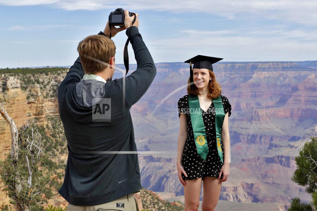 Matt York Andrew Fink takes a photo of recent Baylor University graduate Cady Malachowski at the Grand Canyon Friday, May 15, 2020, in Grand Canyon, Ariz. Tourists are once again roaming portions of Grand Canyon National Park when it partially reopened Friday morning, despite objections that the action could exacerbate the coronavirus pandemic. (AP Photo/Matt York)