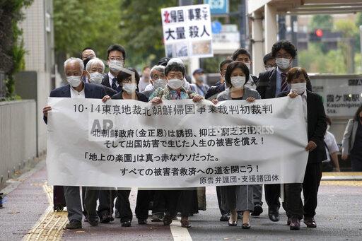 Plaintiffs and their supporters walk toward the Tokyo District Court Thursday, Oct. 14, 2021, in Tokyo. The court is hearing five ethnic Korean residents of Japan and a Japanese national demanding the North Korean government pay compensation over their human rights abuses in that country after joining a resettlement program there that promised a “paradise on Earth,” but without the presence of a defendant - the North’s leader. The banner reads: "Oct. 14 Tokyo District Court the North Korea "Paradise on Earth" campaign first trial. (AP Photo/Eugene Hoshiko)
