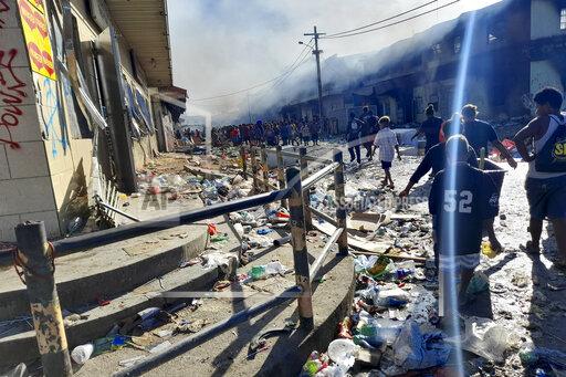 People walk through the looted streets of Chinatown in Honiara, Solomon Islands, Friday, Nov. 26, 2021. Solomon Islands Prime Minister Manasseh Sogavare on Friday blamed foreign interference over his government’s decision to switch alliances from Taiwan to Beijing for anti-government protests, arson and looting that have ravaged the capital Honiara in recent days. (AP Photo/Piringi Charley)