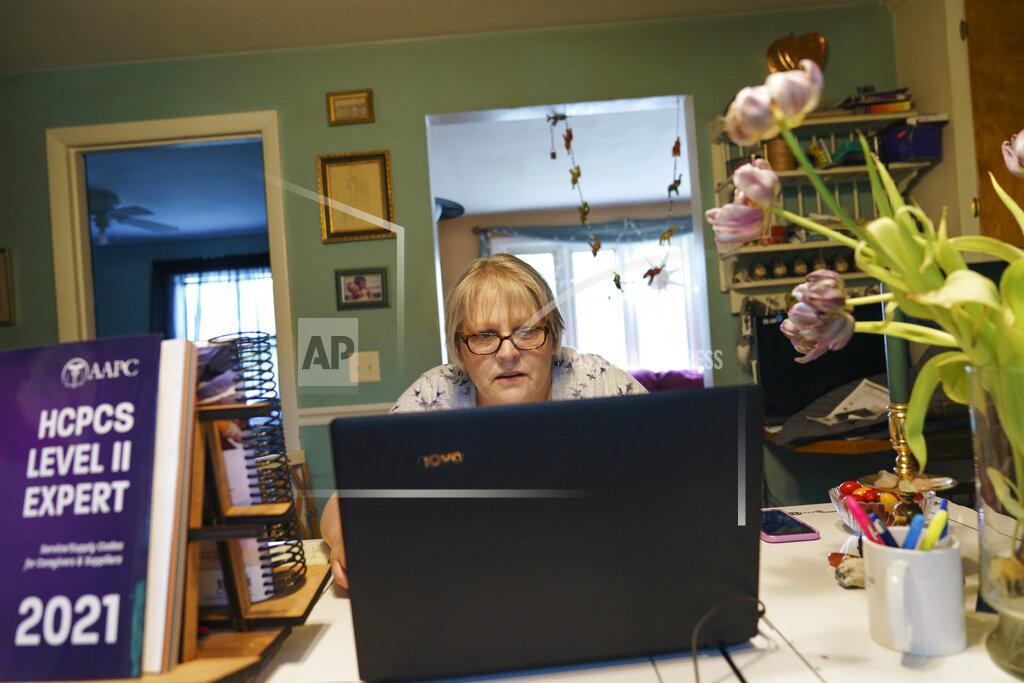 David Goldman Ellen Booth, 57, studies at her kitchen table to become a certified medical coder, in Coventry, R.I., Monday, May 17, 2021. When the restaurant she worked for closed last year, Booth said it gave her "the kick I needed." She started a year-long class to learn to be a medical coder. When her unemployment benefits ran out two months ago, she started drawing on her retirement funds. Booth hopes to pass her upcoming exam and soon hit the job market. (AP Photo/David Goldman)