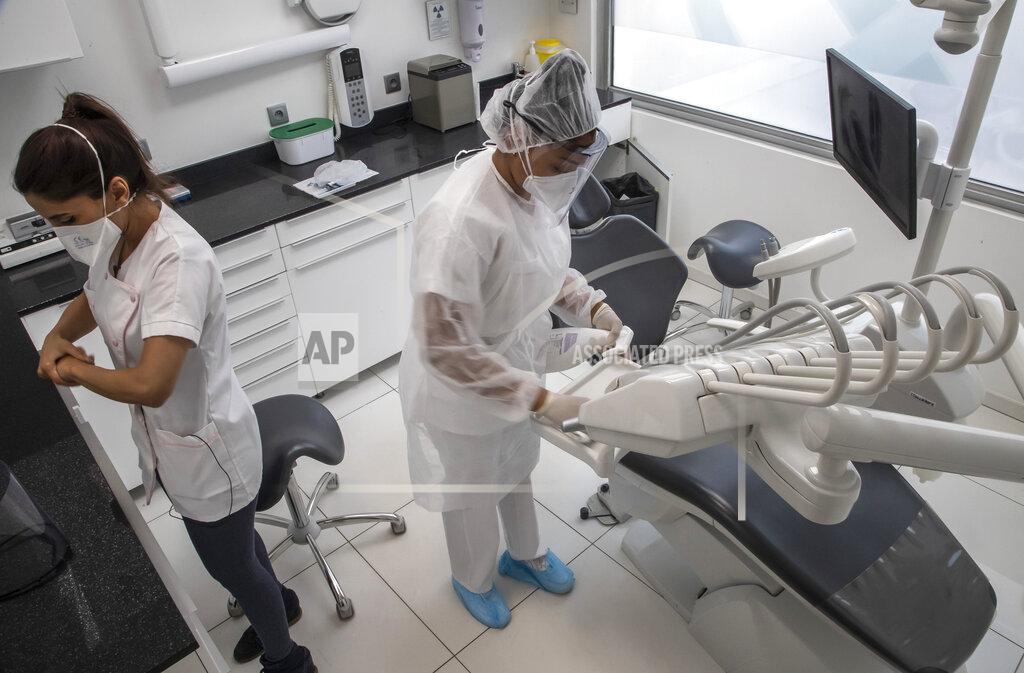 Michel Euler In this photo taken on Wednesday, May 13, 2020, dentist Sabrine Jendoubi, left, and her assistant Margot Daussat prepare for a dental appointment at a dental office in Paris. Those with toothache that suffered through France's two-month lockdown, finally have hope to end the pain. Dental practices are cautiously re-opening and non-emergency dentist appointments are now permitted around the country, as the French government eased confinement restrictions from Monday. (AP Photo/Michel Euler)