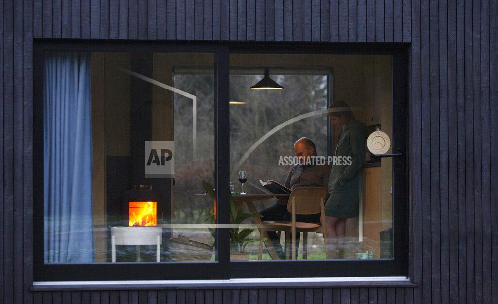 Virginia Mayo Guy De Deyn and his partner Kim Devos enjoy a wood fire as they read a book together in a Slow Cabin in Elewijt, Belgium, Monday, Feb. 15, 2021. With travel restrictions placed on Belgium due to COVID-19, the eco-friendly cabins encourage visitors to slow down and re-connect with nature by immersing themselves closer to home and making new discoveries. (AP Photo/Virginia Mayo)