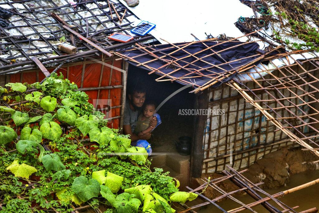 Shafiqur Rahman A Rohingya refugee man sits with his child inside his inundated shelter following heavy rains at the Rohingya refugee camp in Kutupalong, Bangladesh, Wednesday, July 28, 2021. Days of heavy rains have brought thousands of shelters in various Rohingya refugee camps in Southern Bangladesh under water, rendering thousands of refugees homeless. (AP Photo/ Shafiqur Rahman)