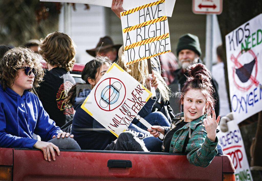 Hunter D'ANtuono FILE - In this March 9, 2021, file photo, students with signs ride in the back of a pickup truck around Flathead High School to protest the Kalispell School District's face mask requirement in Kalispell, Mont. Amid the coronavirus pandemic, Montana's legislature has passed restrictive laws severely curbing public health’s quarantine and isolation powers, increasing local elected officials’ power over local health boards, preventing limits on religious gatherings and banning employers — including in health care settings — from requiring vaccinations for covid, the flu or anything else. (Hunter D'Antuono/Flathead Beacon via AP, File)