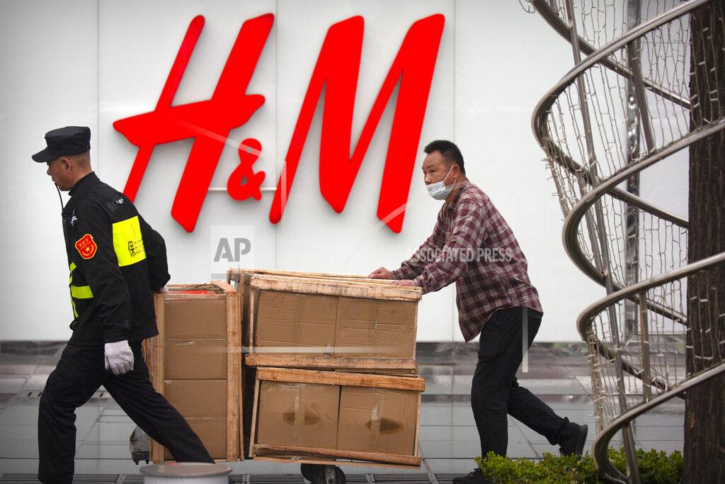 Mark Schiefelbein A security guard helps a worker move boxes past an H&M clothing store at a shopping mall in Beijing, Friday, March 26, 2021. H&M disappeared from the internet in China as the government raised pressure on shoe and clothing brands and announced sanctions Friday against British officials in a spiraling fight over complaints of abuses in the Xinjiang region.(AP Photo/Mark Schiefelbein)