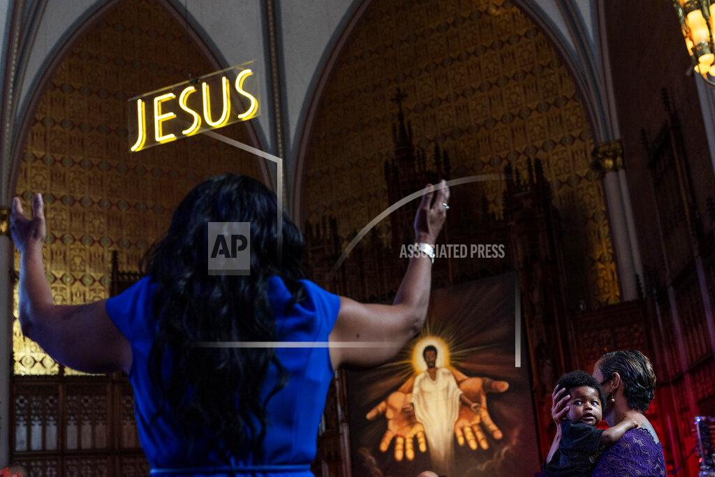 David Goldman Jenny Edwards, right, holds her eight-month-old grandson, Daniel, during a church service at St. Sabina Catholic Church in the Auburn Gresham neighborhood in Chicago, Sunday, Aug. 23, 2020. In harrowing moments, in the sobs of grieving mourners and the incessant wail of sirens, the crises of 2020 have played out painfully within this single Chicago community. (AP Photo/David Goldman)