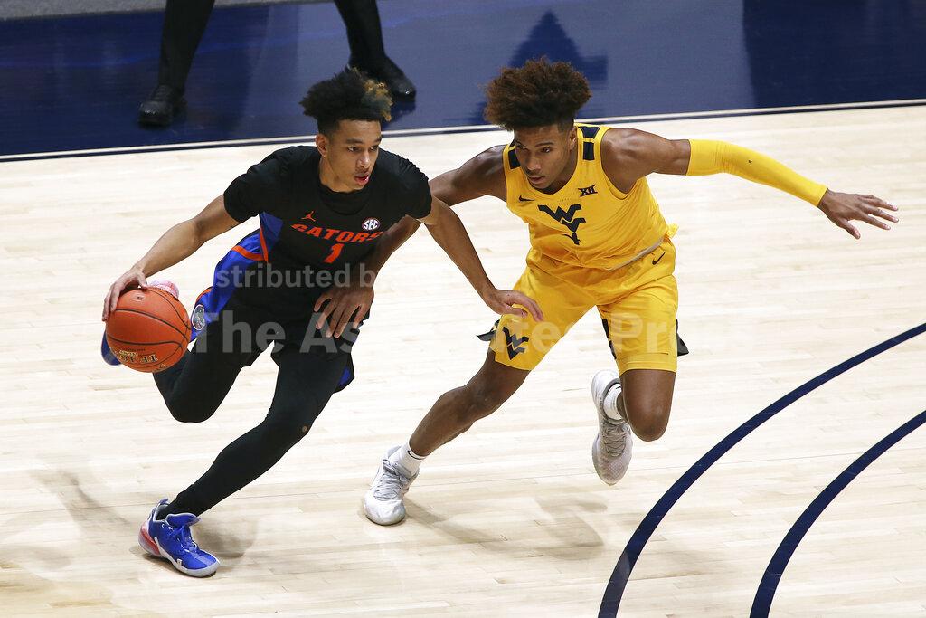 Florida guard Tre Mann (1) is defended by West Virginia guard Miles McBride (4) during the first half of an NCAA college basketball game Saturday, Jan. 30, 2021, in Morgantown, W.Va. (AP Photo/Kathleen Batten)