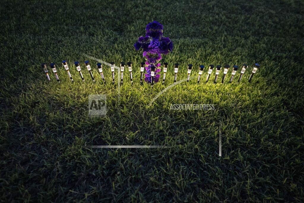 Wong Maye-E Lights illuminate a cross made of flowers at a memorial site in the town square for the victims killed in this week's elementary school shooting on Friday, May 27, 2022, in Uvalde, Texas. (AP Photo/Wong Maye-E)