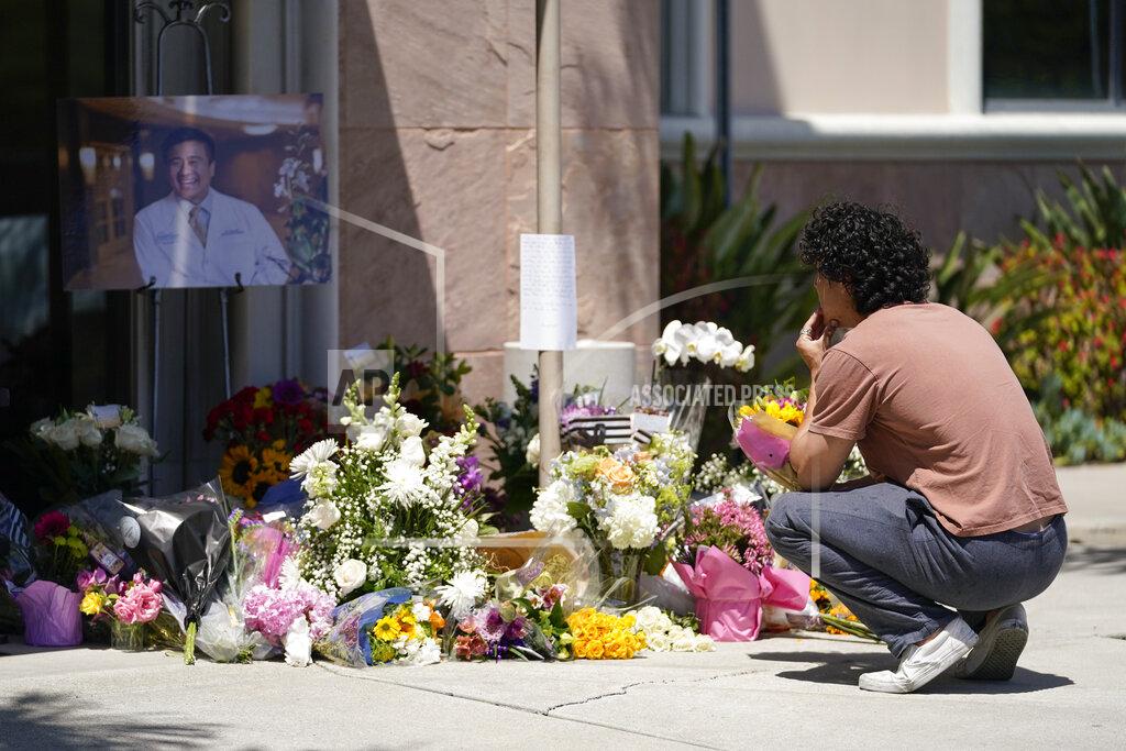 Ashley Landis Gabe Kipers, a neighbor of Dr. John Cheng, kneels at a memorial for him outside his office building on Tuesday, May 17, 2022, in Aliso Viejo, Calif. Cheng, 52, was killed in Sunday's shooting at Geneva Presbyterian Church. (AP Photo/Ashley Landis)