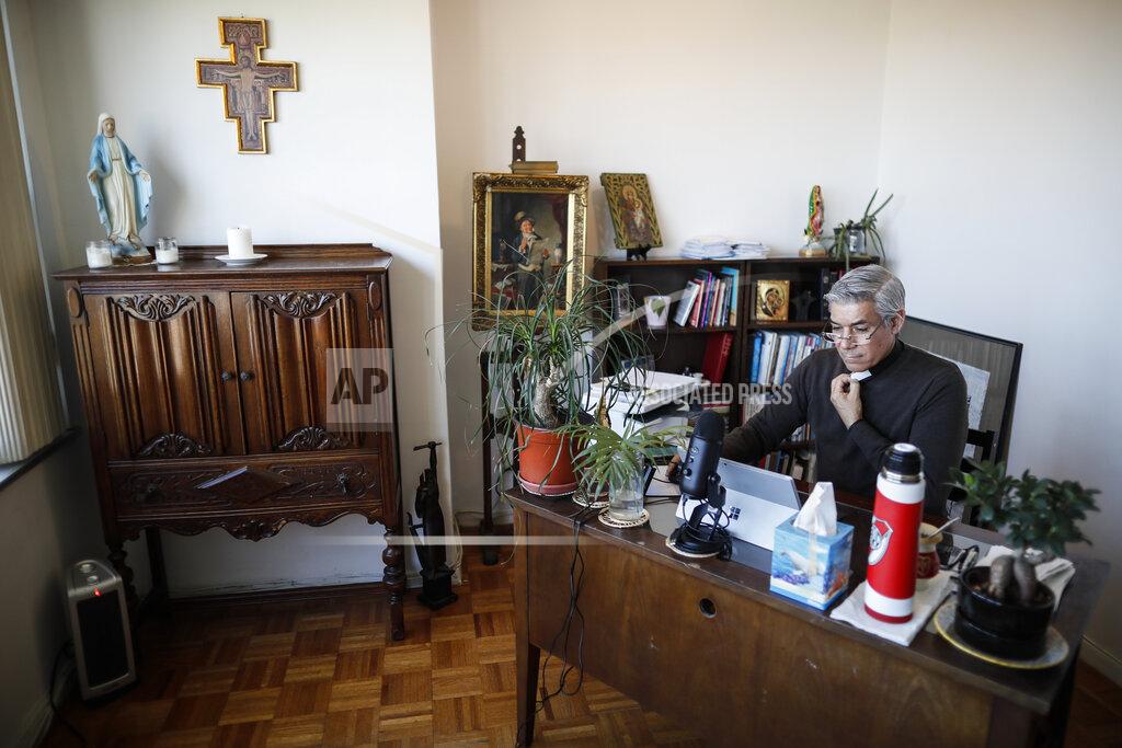 John Minchillo Fabian Arias, a Lutheran pastor with Saint Peter's Church in Manhattan, sits at his desk at his home as he prepares to travel for an in-home funeral service for Graciela Ruiz Martinez, Sunday, May 10, 2020, in the Bronx borough of New York. (AP Photo/John Minchillo)