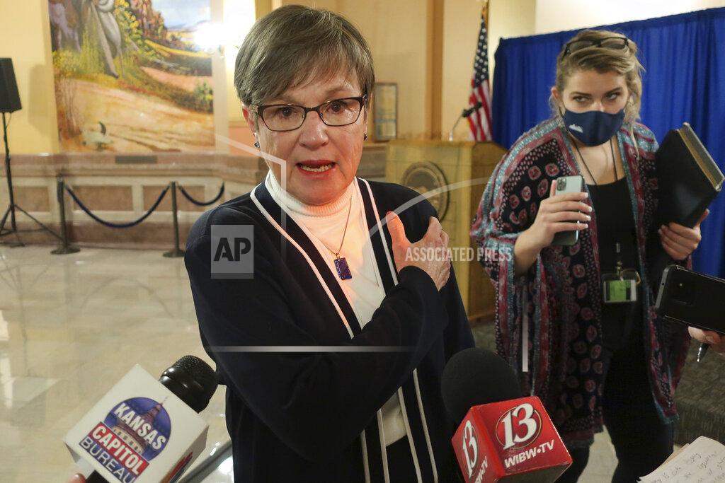 John Hanna Kansas Gov. Laura Kelly gestures to the spot on her left arm where she received a COVID-19 vaccine shot as she tells reporters she had no reaction to it, Monday, Jan. 4, 2021, at the Statehouse in Topeka, Kan. Kelly says she is very comfortable with the distribution of vaccines across the state, saying federal data showing Kansas lagging behind all others in inoculations is the result of a lag in reporting. (AP Photo/John Hanna)