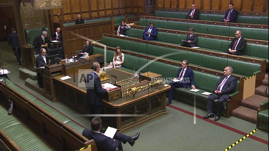 Uncredited In this image taken from video, Britain's Foreign Secretary Dominic Raab, center left standing, speaks during Prime Minister's Questions in the House of Commons, London, Wednesday April 22, 2020. U.K. legislators and most parliamentary staff were sent home in late March as part of a nationwide lockdown to slow the spread of the new coronavirus. A few dozen legislators sat, well-spaced, in the Commons, and agreed on arrangements for lawmakers to ask questions from home using videoconferencing program Zoom, beamed onto screens erected around the wood-paneled chamber. (House of Commons via AP)