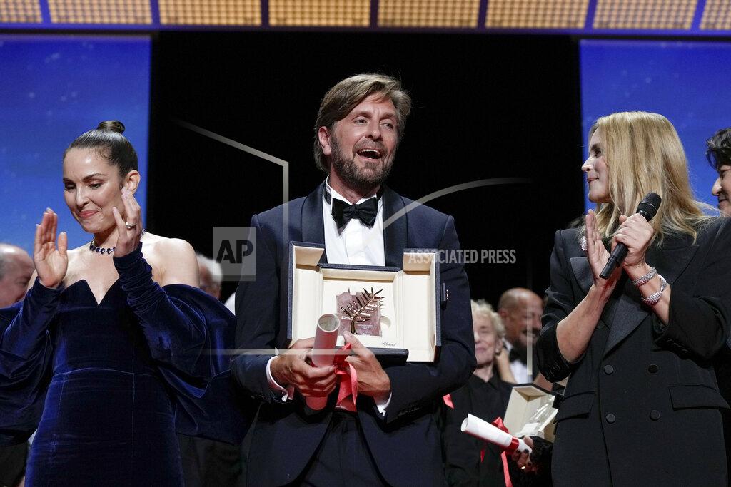 Joel C Ryan Writer/director Ruben Ostlund, center, accepts the Palme d'Or for 'Triangle of Sadness' as jury member Noomi Rapace, left, and Virginie Efira look on during the awards ceremony of the 75th international film festival, Cannes, southern France, Saturday, May 28, 2022. (Photo by Joel C Ryan/Invision/AP)