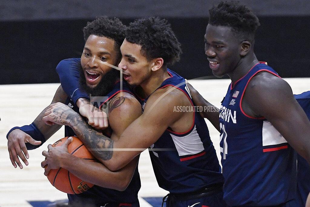 Jessica Hill Connecticut's James Bouknight, center, and Adama Sanogo, right, celebrate with R.J. Cole after Cole gained possession of the ball as the clock ran out at the end of an NCAA college basketball game against Southern California, Thursday, Dec. 3, 2020, in Uncasville, Conn. (AP Photo/Jessica Hill)