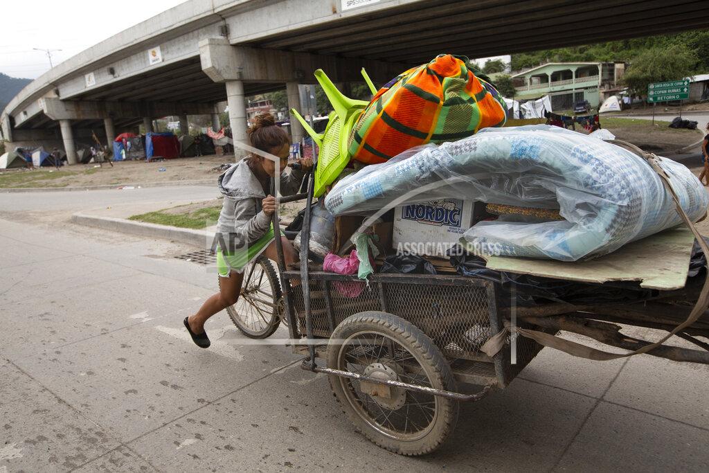 Moises Castillo Floria Sarai Calix pushes her belongings in hopes of finding a safer area to camp out with her son after losing their home in the Chamelecon neighborhood to hurricanes Eta and Iota, on the outskirts of San Pedro Sula, Honduras, Monday, Jan. 11, 2021. The devastation wrought by November's hurricanes and the economic damage of the COVID-19 pandemic has added to the forces that drive Hondurans to migrate: poverty and gang violence. (AP Photo/Moises Castillo)
