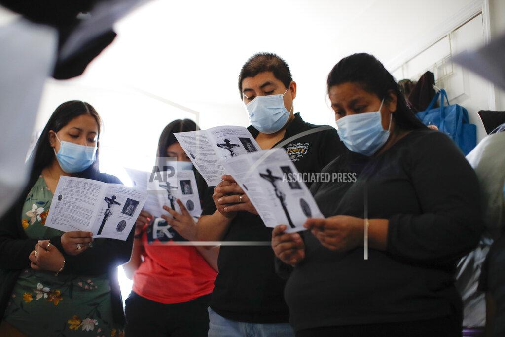 John Minchillo Family members follow an in-home funeral service offered by Fabian Arias, a Lutheran pastor with Saint Peter's Church in Manhattan, left, for Graciela Ruiz Martinez who died of COVID-19, Sunday, May 10, 2020, in the Queens borough of New York. (AP Photo/John Minchillo)