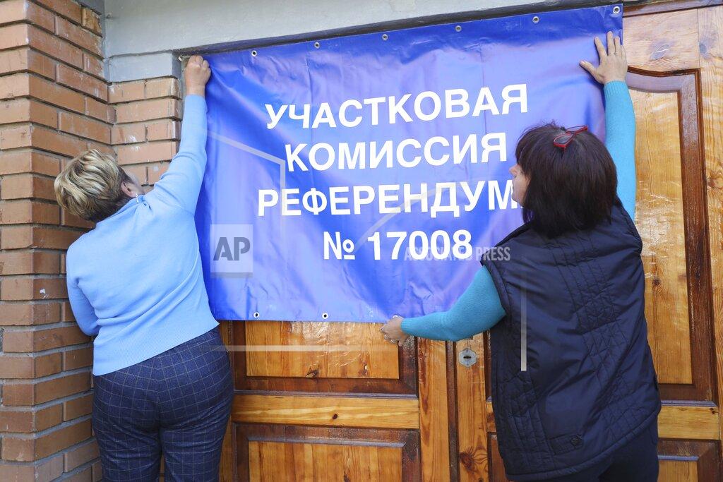 Uncredited Members of Donetsk regional referendum committee attach a poster with writing reading "District referendum committee nr. 17008" on a door of polling station, prior to a referendum in Donetsk, Donetsk People's Republic controlled by Russia-backed separatists, eastern Ukraine, Thursday, Sept. 22, 2022. The separatist leaders of four Russian-controlled areas of Ukraine say they are planning to hold referendums this week for the territories to become part of Russia as Moscow loses ground in the war it launched. The votes will be held in the Luhansk, Kherson and partly Russian-controlled Zaporizhzhia and Donetsk regions. (AP Photo)