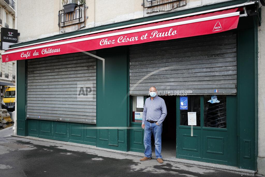 Francois Mori Cesar, from Portugal, stands in front of his closed bar, in Paris, Tuesday, Oct. 6, 2020. French authorities have placed the Paris region on maximum virus alert on Monday, banning festive gatherings and requiring all bars to close but allowing restaurants to remain open, as numbers of infections are rapidly increasing. (AP Photo/Francois Mori)