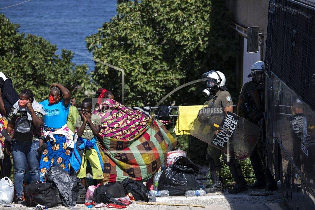 Migrants take part in a rally as riot police block the road near Mytilene town, on the northeastern island of Lesbos, Greece, Friday, Sept. 11, 2020. Thousands of protesting refugees and migrants left homeless on the Greek island of Lesbos after fires destroyed the notoriously overcrowded Moria camp have gathered on a road leading to the island's main town, demanding to be allowed to leave. (AP Photo/Petros Giannakouris)