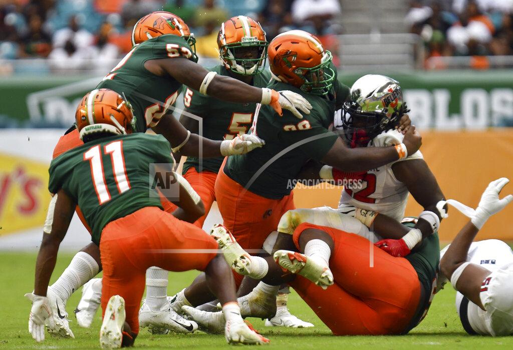 Jim Rassol Jackson State running back Peytton Pickett (22) is brought down by Florida A&M defensive linemen Donald Hall, bottom, and Stanley Mentor (98) in the fourth quarter of an NCAA college football game, Sunday, Sept. 5, 2021, in Miami Gardens, Fla. (AP Photo/Jim Rassol)